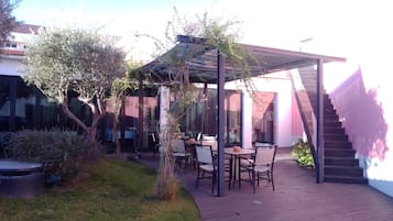 An outdoor patio area with a pergola, seating, and a staircase.