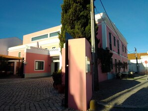 Un edificio rosa con una calle adoquinada al frente.
