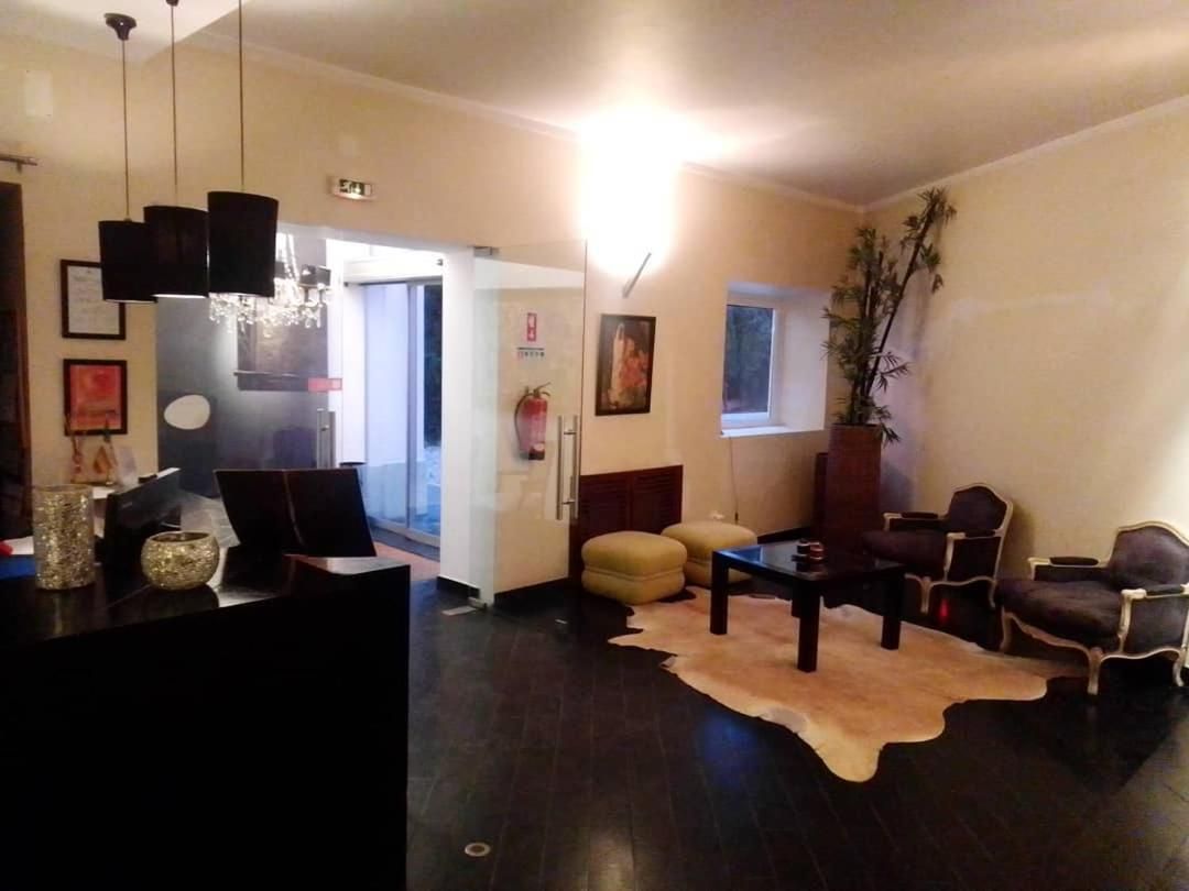 A living room with a dark wood floor, a black reception desk, a chandelier, and a large window with a view.