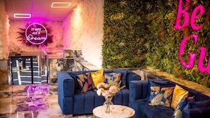 A modern lounge area with a blue sofa, a marble floor, and a green wall with a vertical garden. - Hotel Holloway (Birmingham)