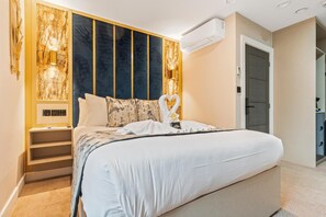 A modern bedroom with a large bed, built-in shelving, a wall-mounted air conditioner, and a door leading to another room. - Hotel Holloway (Birmingham)