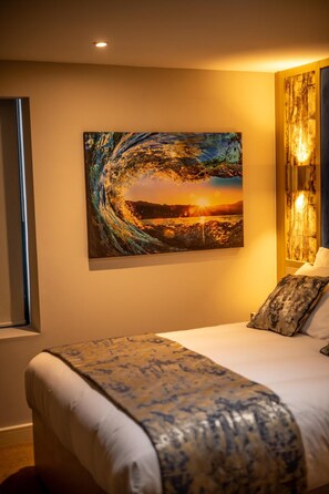 A hotel room with a large painting, a bed with a patterned bedspread, and a window with a view. - Hotel Holloway (Birmingham)