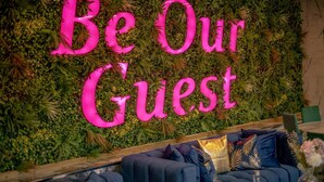 A wall with a 'Be Our Guest' sign surrounded by lush greenery. - Hotel Holloway (Birmingham)