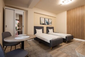 A hotel room with two beds, a dining table, and a chair. - Apart Hotel Bonjour Cluj (Cluj-Napoca)