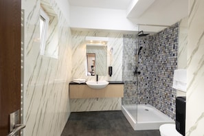 A modern bathroom with a marble wall, a sink, a mirror, a shower, and a toilet. - Apart Hotel Bonjour Cluj (Cluj-Napoca)