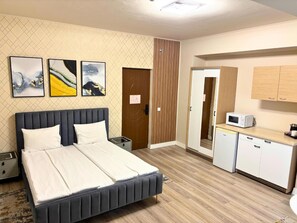 A hotel room with a bed, a small desk with a microwave, and a cabinet. - Apart Hotel Bonjour Cluj (Cluj-Napoca)