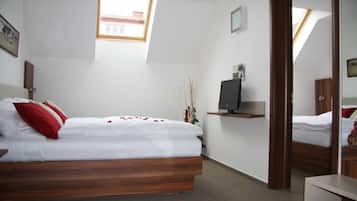 Een slaapkamer met een bed, bureau, televisie, raam en spiegel.