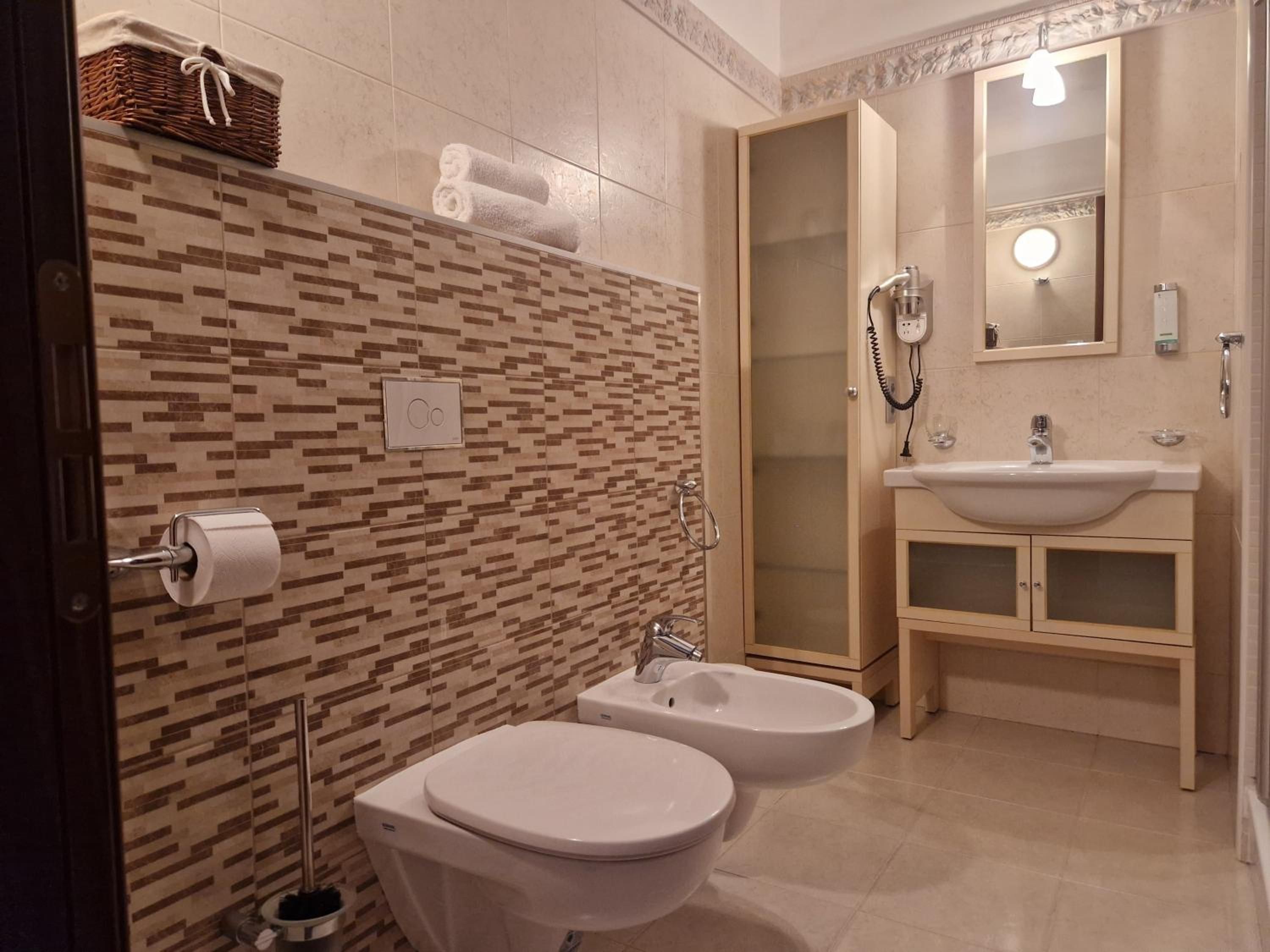 Een badkamer met twee toiletten, een bidet, een wastafel en een spiegel.
