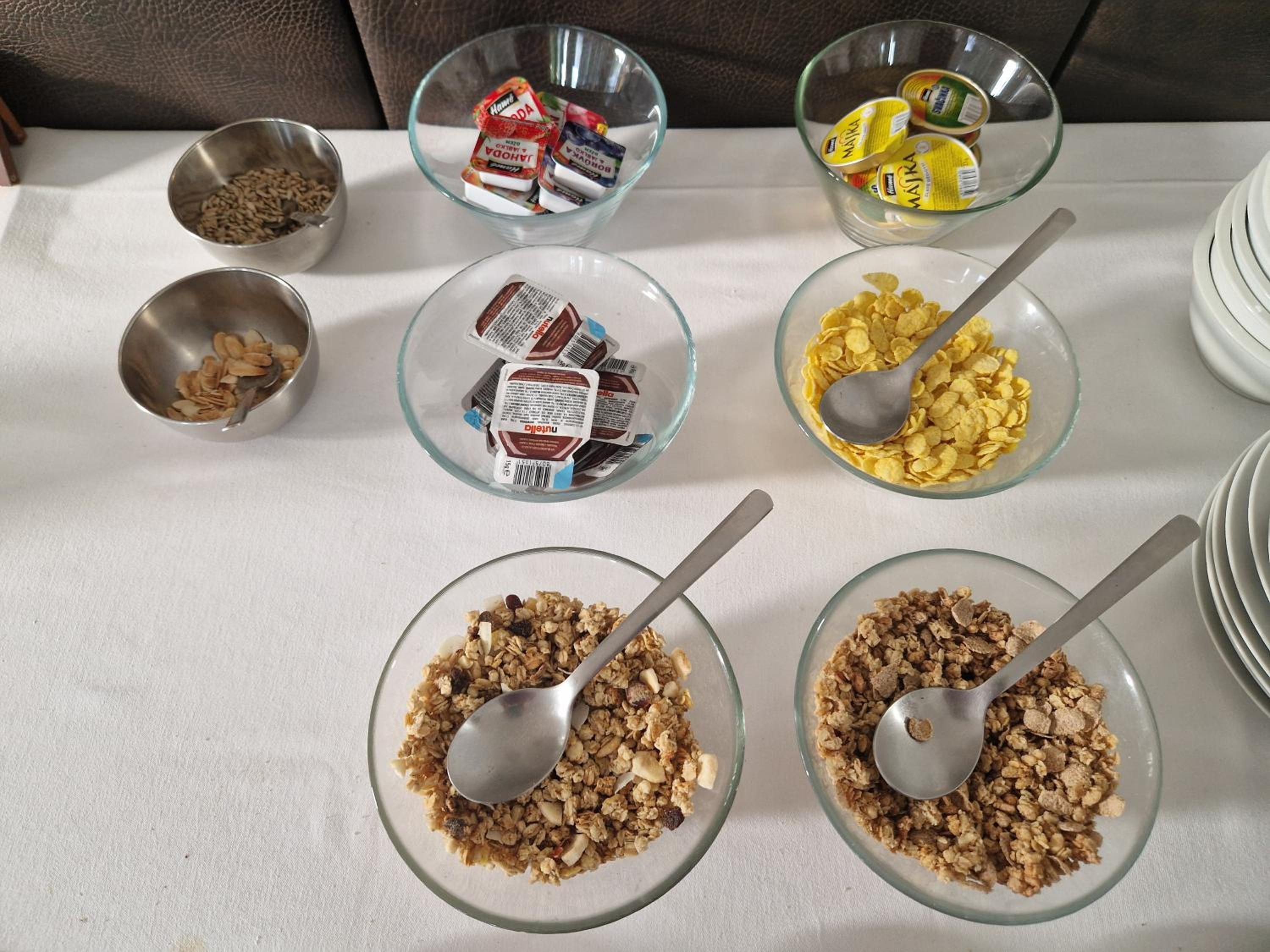 Une table où sont présentés divers aliments, notamment des céréales, des noix et des en-cas emballés.