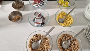 Een tafel met diverse etenswaren, zoals ontbijtgranen, noten en snacks.