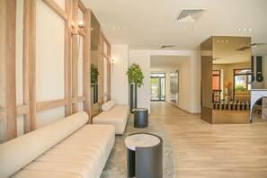 Um hall de hotel moderno com um balcão de recepção extenso, área de estar e vista para o exterior.