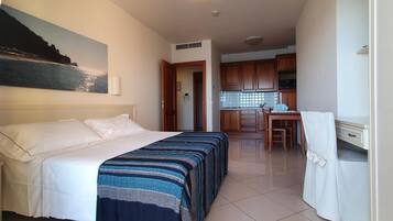 Una camera d'albergo con un letto, una scrivania e un angolo cottura.