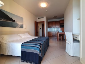 Una habitación de hotel con cama, escritorio y kitchenette.