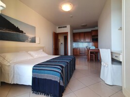 Una camera d'albergo con un letto, una scrivania e un angolo cottura.