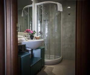 Un baño con ducha de vidrio, lavamanos con espejo y mueble.