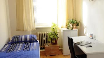 Ein gemütliches Schlafzimmer mit Bett, Schreibtisch und Heizkörper.