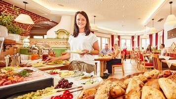 A buffet area with a variety of food options and a waiter serving guests.