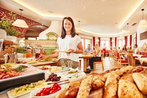 Buffet-alue, jossa on monipuolinen valikoima ruokia, ja tarjoilija huolehtii vieraista.