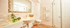 Ein Badezimmer mit Waschbecken, Spiegel, Handtuchhalter und Duschbereich.