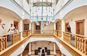 Ein geräumiger Innenraum mit einer zentralen Treppe, Holzwertungen und hängenden Leuchten.