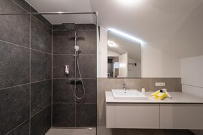 Un baño moderno con ducha, lavamanos y espejo.