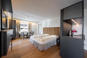 Una habitación de hotel moderna con cama, escritorio, silla y kitchenette.
