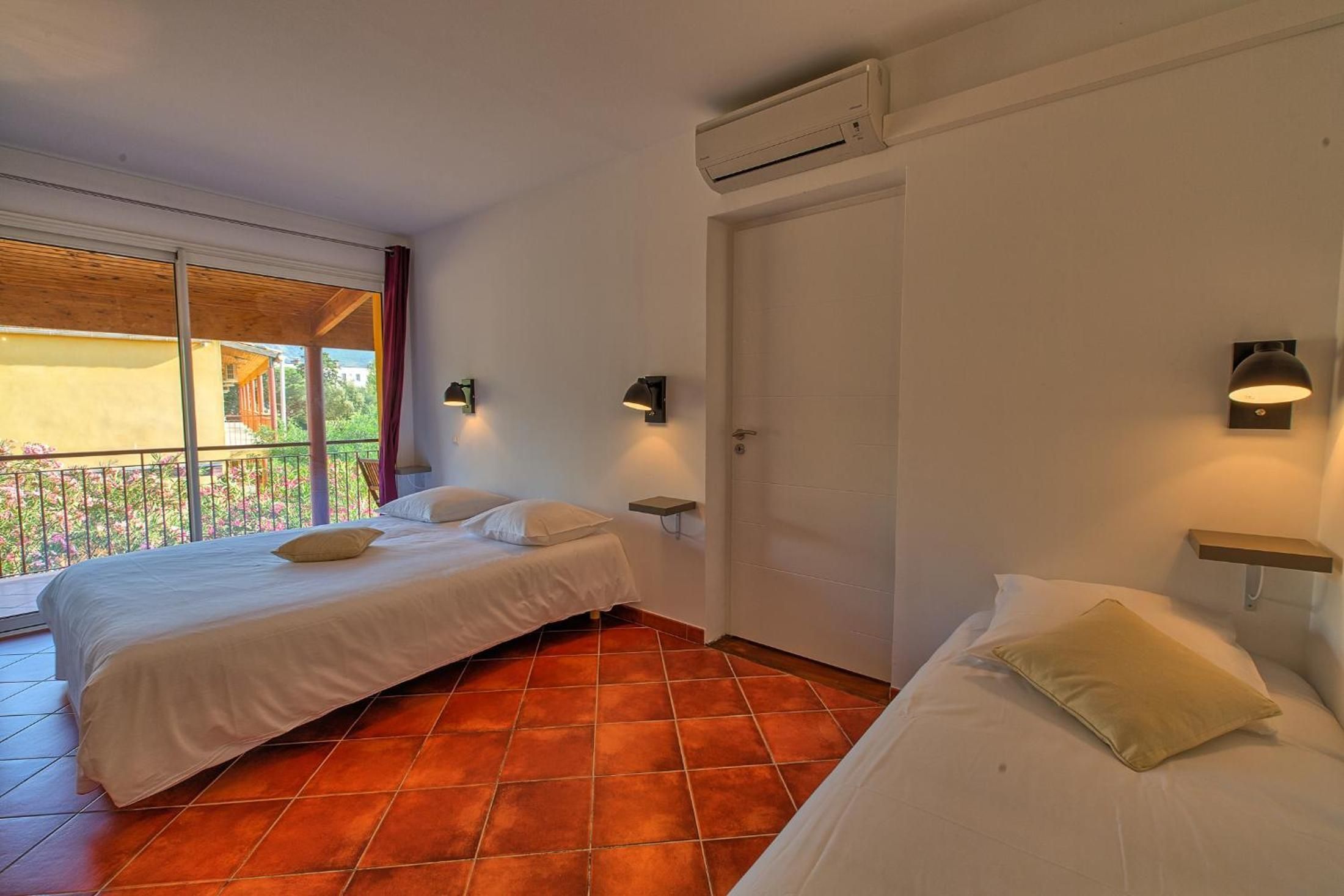 Een hotelkamer met twee bedden, een balkon, een airconditioning en een deur.