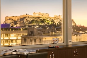 A hotel room with a view of a historic building on a cliff. - Aria Acropolis Suites (Athens)