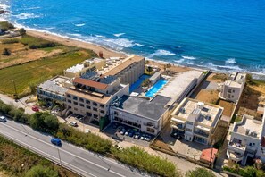 A coastal hotel with a rooftop pool, adjacent to a beach.