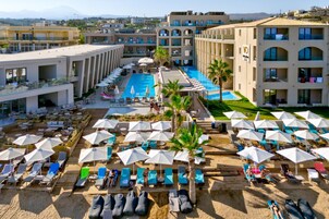 Un hotel con piscina central, varias zonas de descanso con sombrillas y vistas de los edificios circundantes.
