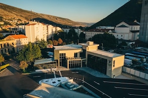 A modern hotel with a central courtyard, surrounded by buildings and a mountainous backdrop. - Hotel Verso (Mostar)