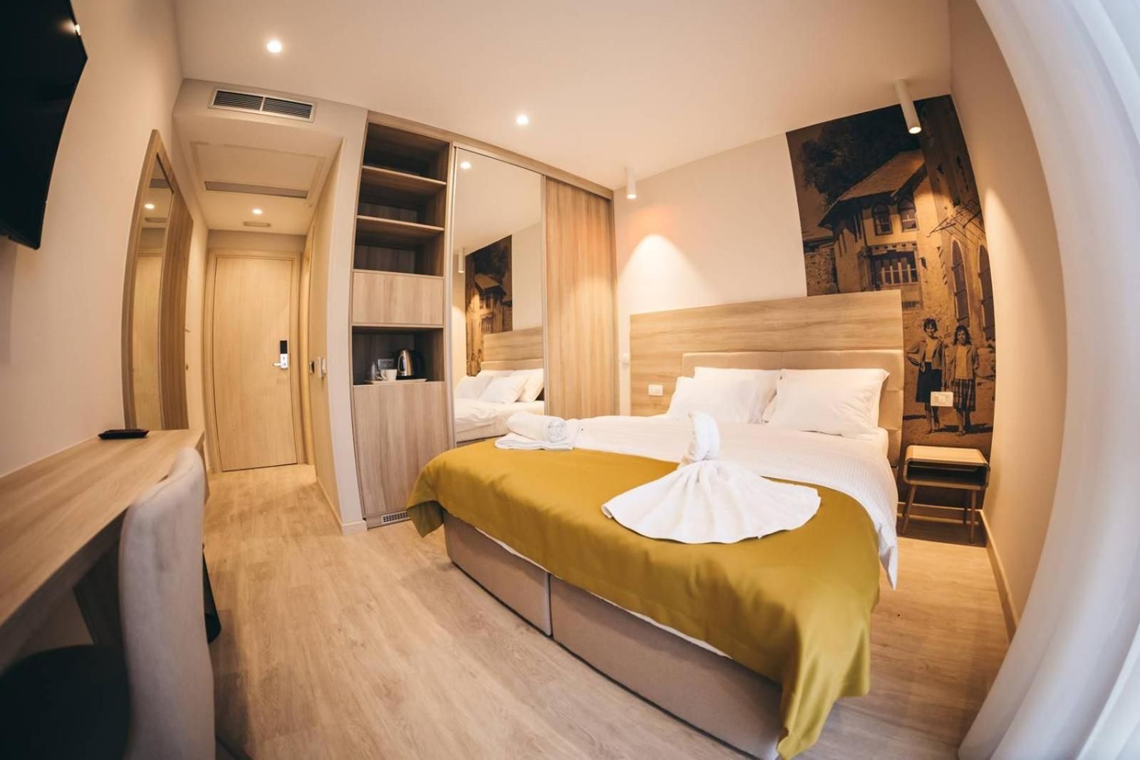 A hotel room with a bed, a bedside table, a wardrobe, and a mirror.