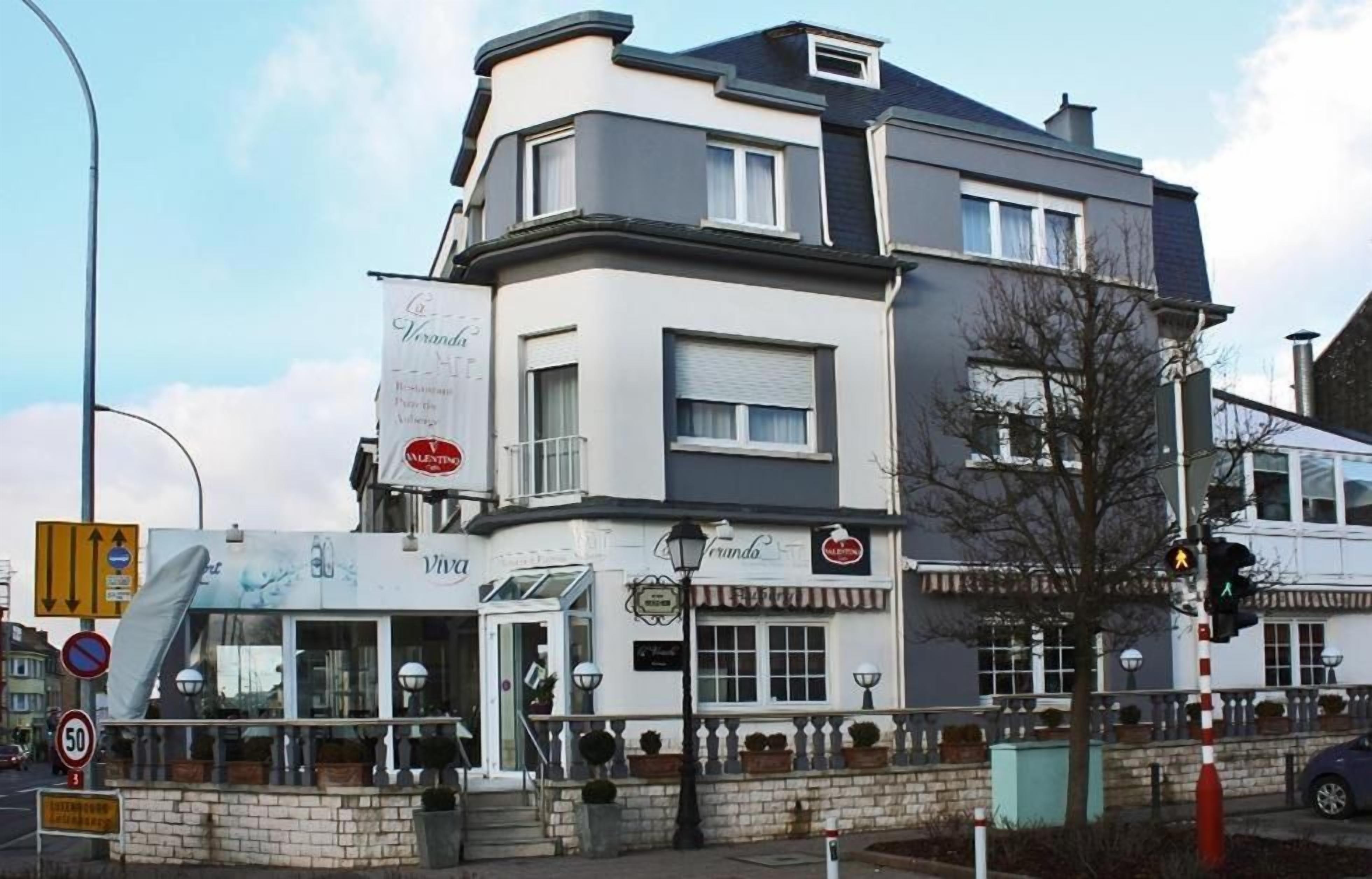 Um edifício de vários andares com um restaurante chamado 'Veranda' no andar térreo.