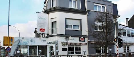 Um edifício de vários andares com um restaurante chamado 'Veranda' no andar térreo.