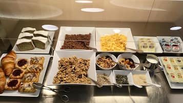 A buffet with various food items including pastries, cereals, and spreads.