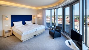 A hotel room with a large bed, a desk, a chair, and a TV. - Hotel Erwin Junker (Holice)