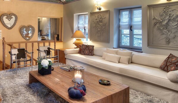 A cozy living room with a wooden coffee table, a sofa, a chair, and decorative wall art. - 5 Senses (Zagori)