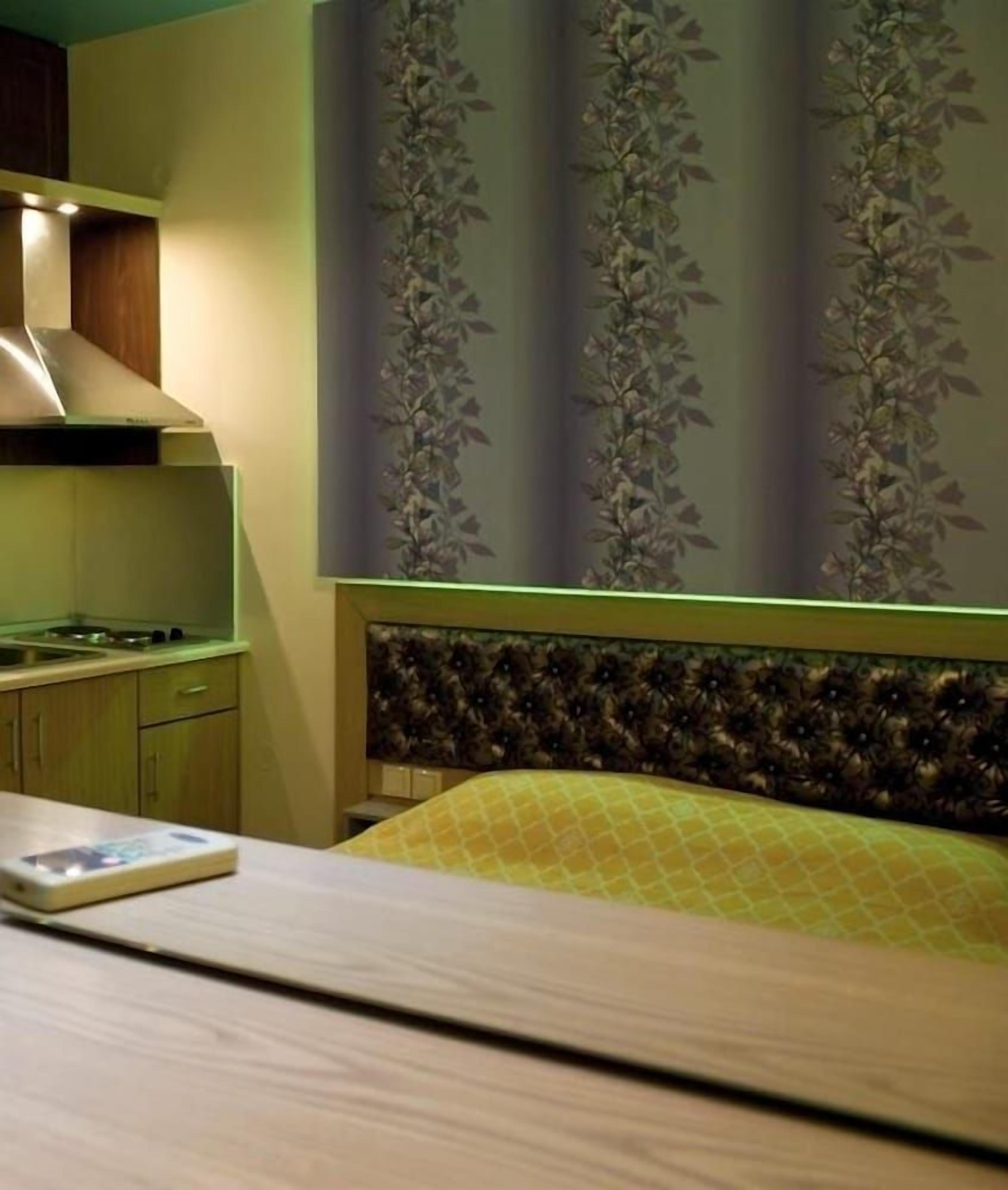 A bedroom with a bed, a bedside table, a nightstand, and a window with curtains.