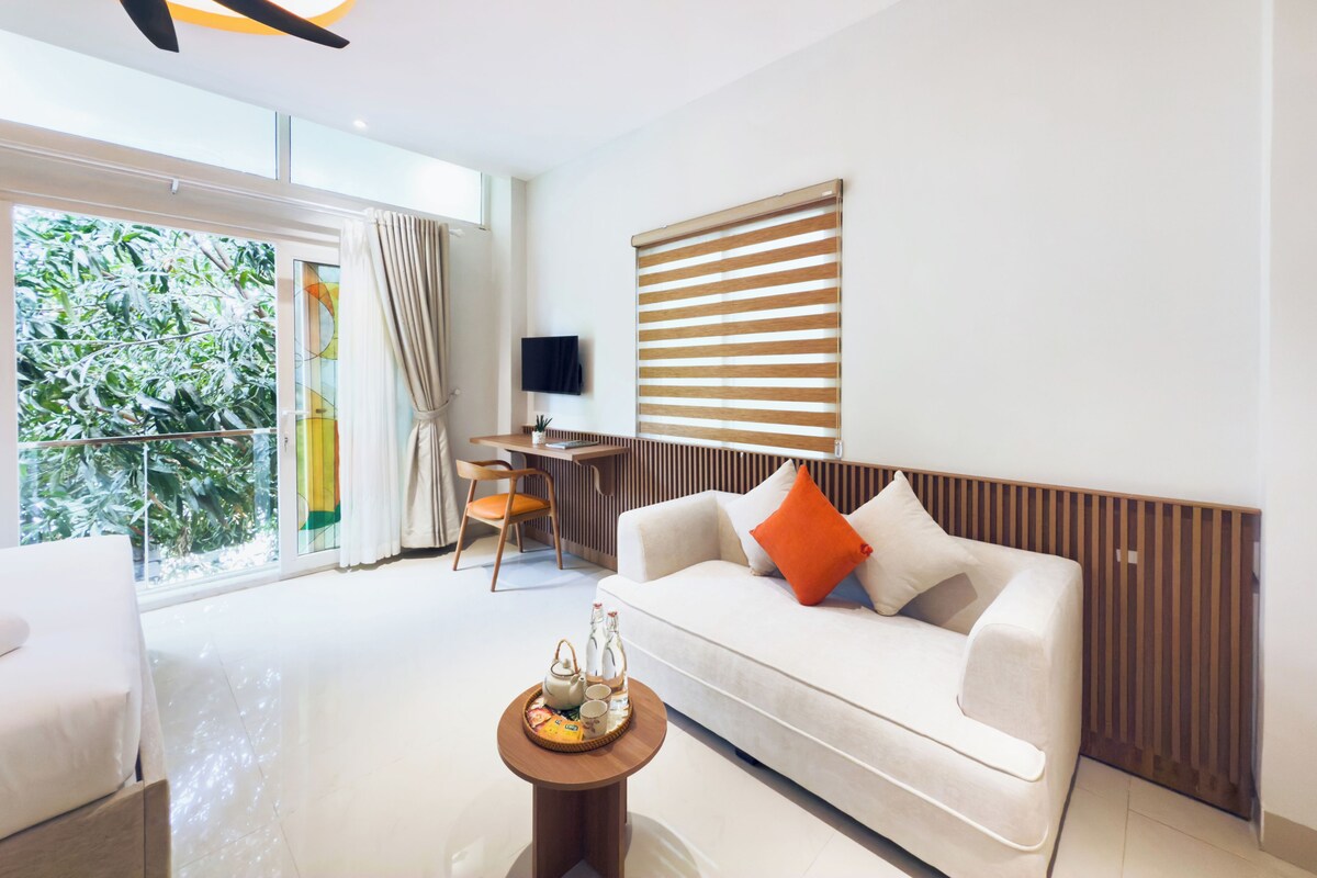Un salon moderne avec un canapé blanc, une table d’appoint en bois et un téléviseur fixé au mur.