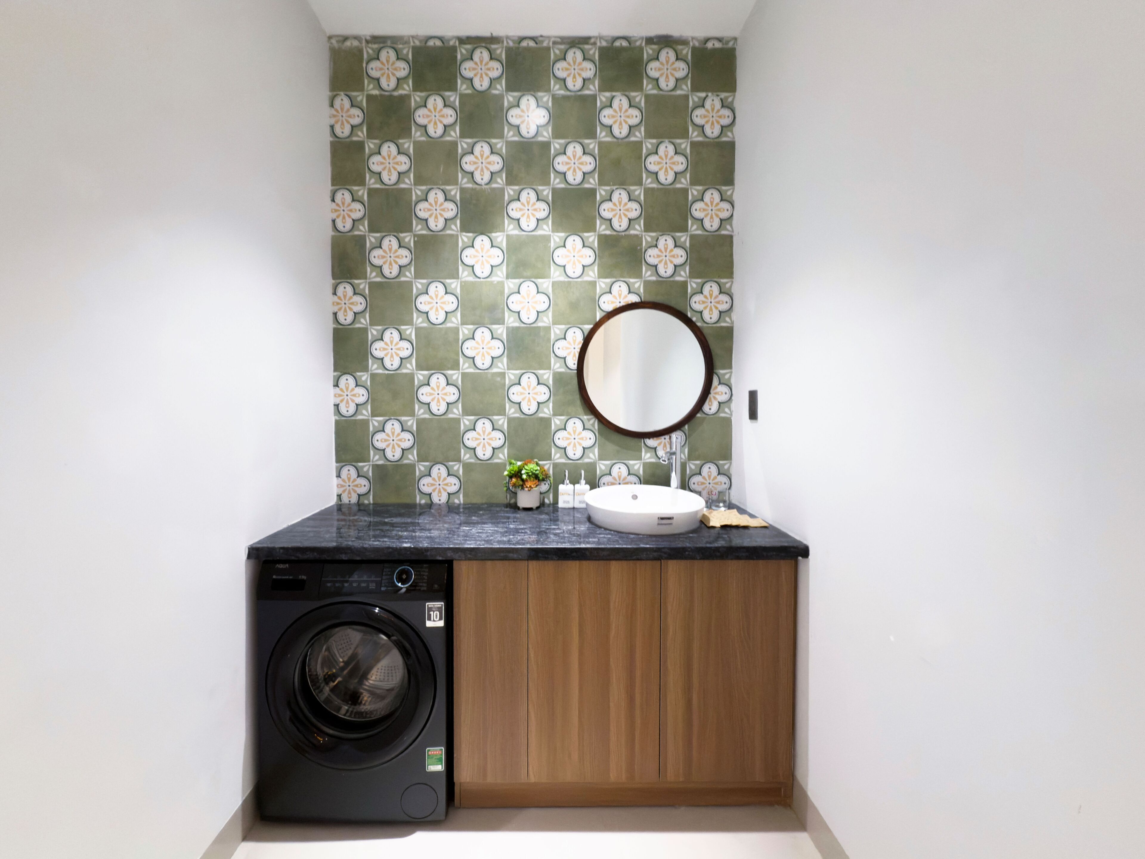 A compact laundry room with a washing machine, a sink, and a wooden cabinet.