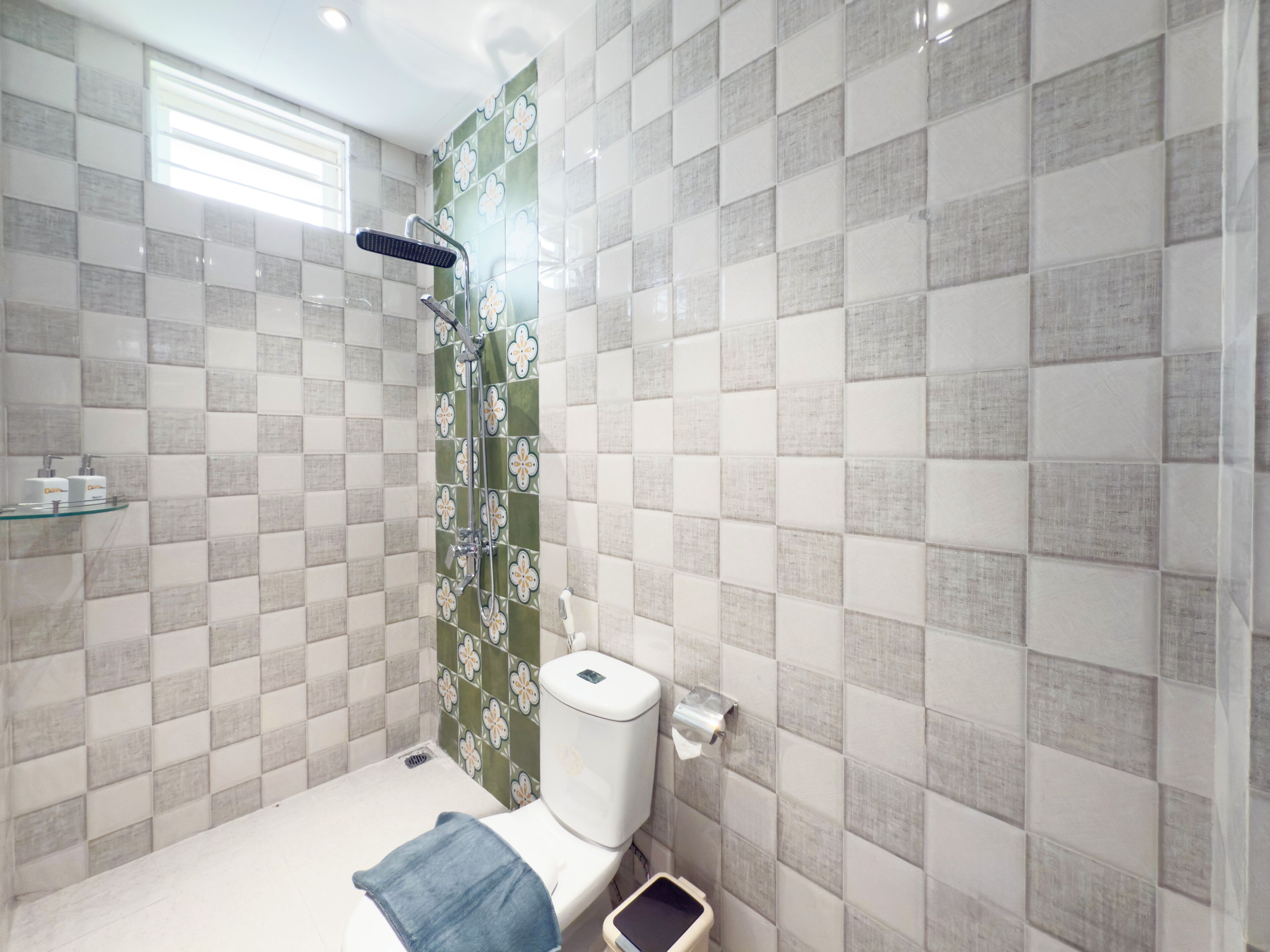 Un bagno con doccia, WC e ripiano in vetro con articoli da toilette.