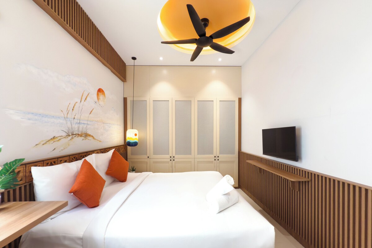 Une chambre d’hôtel moderne équipée d’un lit, d’un bureau, d’une télévision et d’un ventilateur de plafond.