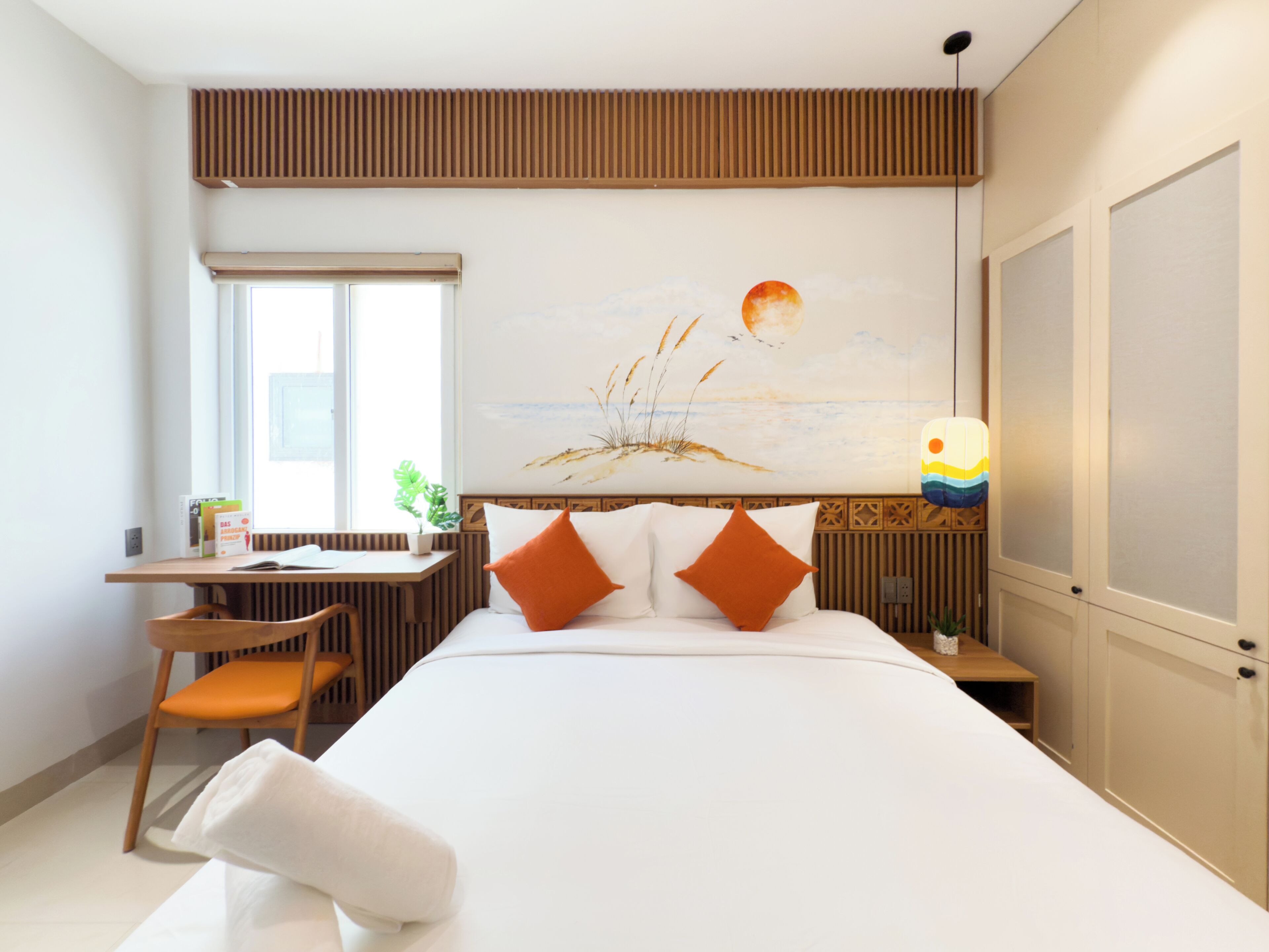 Habitación de hotel con cama, escritorio, silla, ventana y un cuadro en la pared.