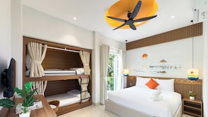 Habitación de hotel con literas, un escritorio con una planta, cama con ropa de cama blanca, ventilador de techo y un cuadro de una playa.