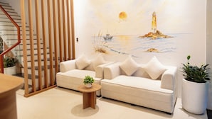 Un salón con un sofá, una mesita de madera y un cuadro de un faro.