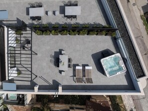 Vista aérea de um terraço com mobiliário ao ar livre, uma banheira de hidromassagem e plantas em vasos.