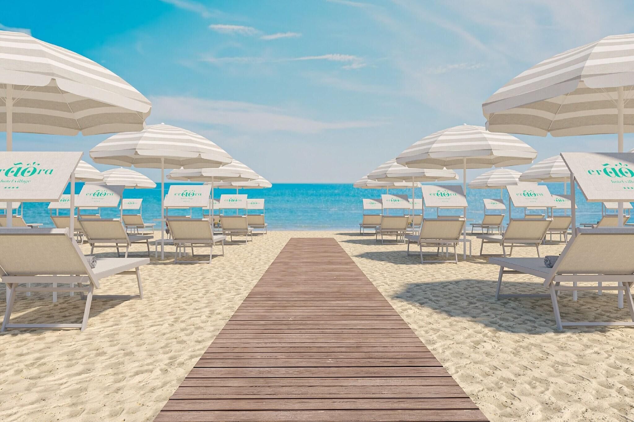 Una spiaggia con una passerella in legno che conduce a lettini e ombrelloni, ognuno contrassegnato da 'Hotel Village'.