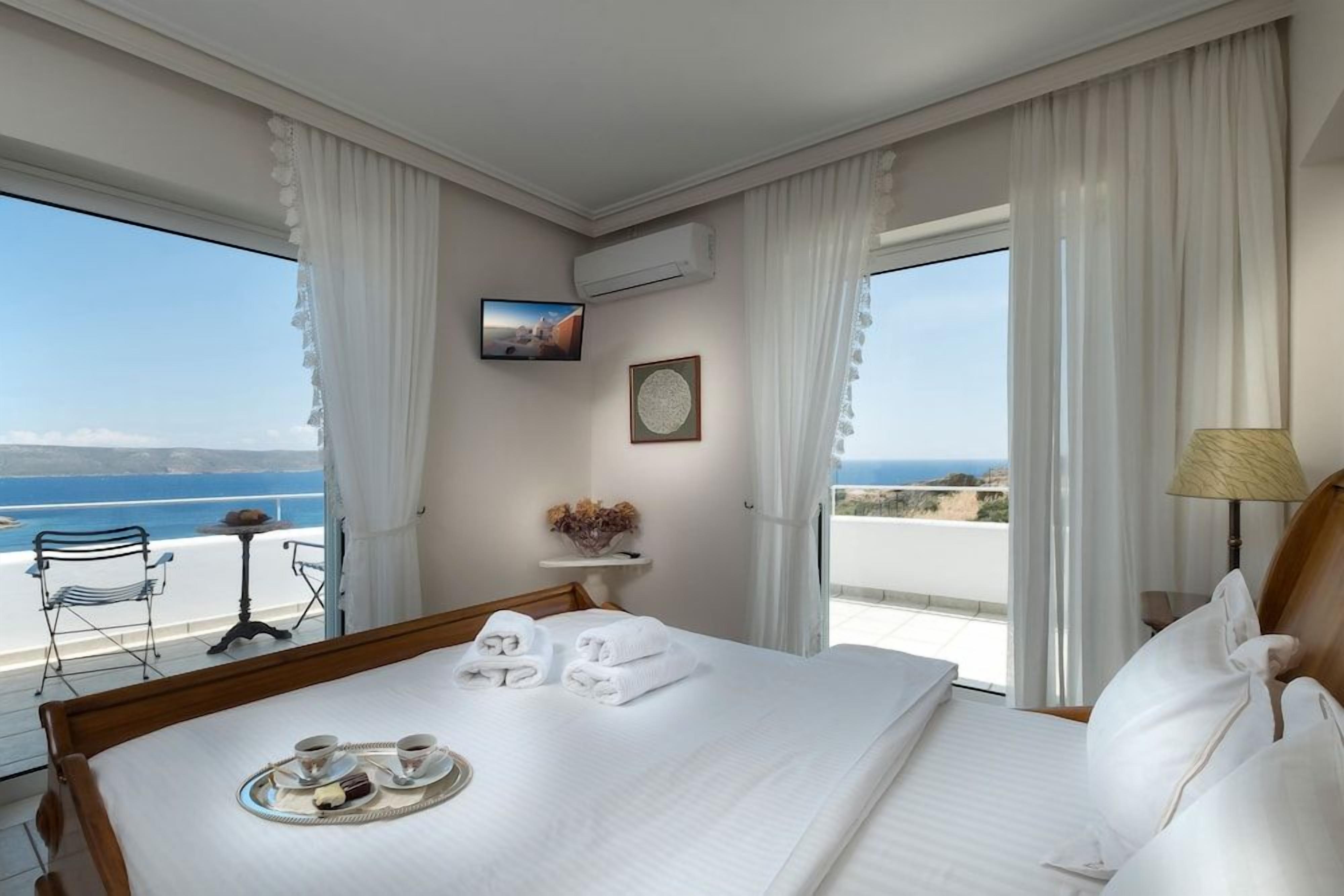 Una habitación de hotel con una cama, una bandeja con alimentos para el desayuno, un televisor y vistas al mar.