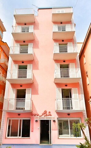 Un edificio de varios pisos con balcones, un cartel que indica restaurante y un cielo despejado.