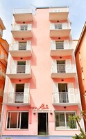 Un edificio de varios pisos con balcones, un cartel que indica restaurante y un cielo despejado.